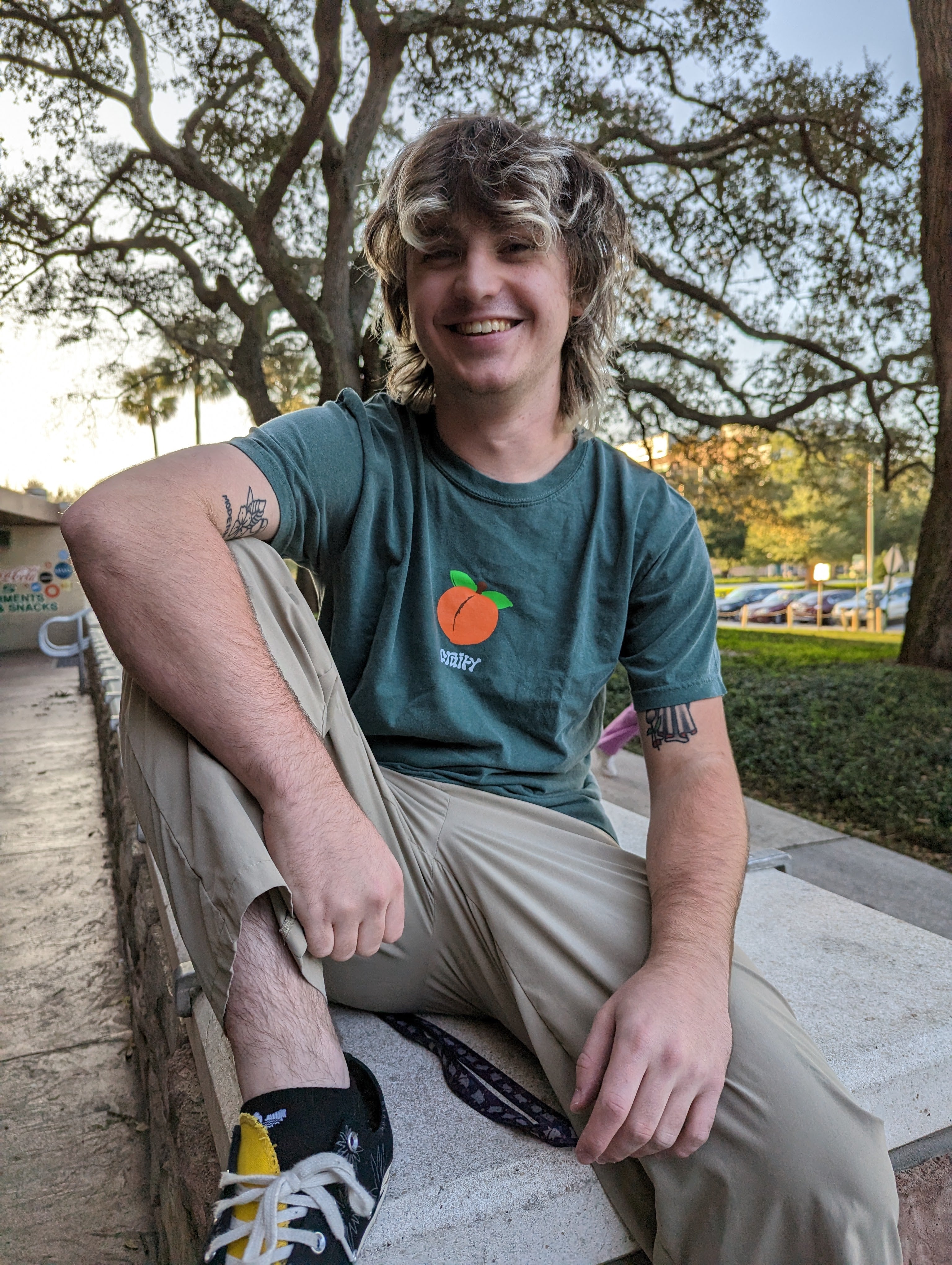 Peach Fruity Shirt Outside Posing Smiling Dark Green T-Shirt Subtle Gay Pride Queer Fashion LGBTQ Clothing Inclusive Apparel